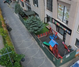 Bina ile yol arasındaki bahçe şeridinde renkli oyun alanı, havadan çekim